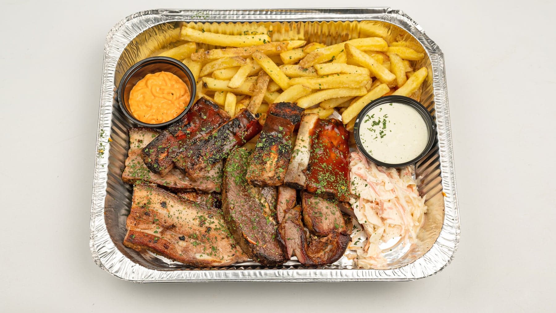 The Smokehouse Share platter for one to two, piled with fire-cooked meats, fries, coleslaw and sauces